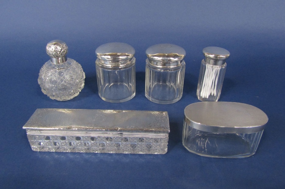A collection of five silver lidded glass dressing/scent jars together with a further topped cut