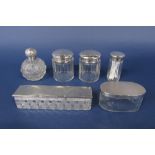 A collection of five silver lidded glass dressing/scent jars together with a further topped cut