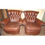A pair of vintage club or library chairs, upholstered in a medium brown leather with brass stud work