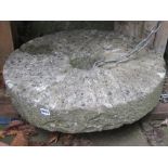 An old carved natural stone millstone, 61 cm (2ft) in diameter