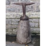 An old antique cast iron anvil set/surmounted on a wooden tapered block