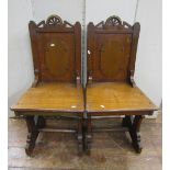 A pair of Victorian Gothic revival oak hall chairs with chamfered frames, raised panelled backs