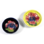 TWO MOORCROFT POTTERY BOWLS IN THE 'HIBISCUS' PATTERN, ON A BLUE AND YELLOW GROUND RESPECTIVELY (