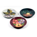 THREE MOORCROFT POTTERY PIN DISHES, TUBELINED AND DECORATED WITH FLORAL DESIGNS, WITH IMPRESSED