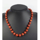 CARVED FACETED CORAL AND GLASS BEAD NECKLACE WITH A YELLOW METAL CLASP STAMPED 750, GROSS WEIGHT