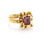 A PINK TOURMALINE RING centred by a claw-set baguette-cut tourmaline within a floral design, the