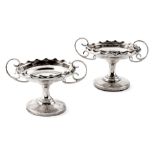 A PAIR OF SILVER TAZZAS, CHESTER 1913 each with a wavy rim, scroll handles, on a circular base 8,5cm