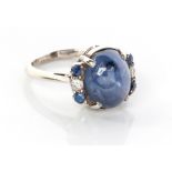 A SAPPHIRE AND DIAMOND RING centred by a claw-set cabochon sapphire flanked by a claw-set old-cut