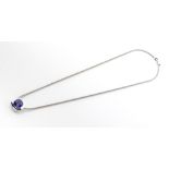 A TANZANITE PENDANT the tube-set square-cut tanzanite in a conforming plain surround, on a link