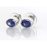 A PAIR OF TANZANITE STUDS each tube-set oval mixed-cut tanzanite in 18ct white gold (2)