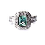 AN EMERALD AND DIAMOND RING claw-set to the centre with a single natural emerald-cut emerald,