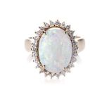 AN OPAL AND DIAMOND RING claw-set to the centre with a natural oval opal measuring 14 by 11mm,