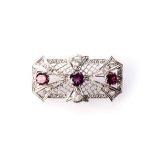 A PLATINUM BROOCH claw-set with three round brilliant-cut rhodolite with a combined weight of 3,0