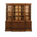 A GEORGE III STYLE MAHOGANY BREAKFRONT BOOKCASE the moulded cornice above four astragal glazed doors