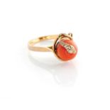 A CORAL RING Designed as a stylised snake coiled around a rounded coral bead measuring approximately