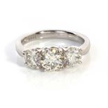 A THREE STONE DIAMOND RING Claw set to the centre with a round brilliant cut diamond flanked by