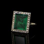 A green paste ring in a white metal mount with a halo of white stones, ring size J 1/2,