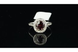 Garnet and diamond cluster ring, central oval cut garnet, surrounded by round cut diamonds and