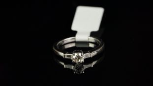 Three stone diamond ring, central round brilliant cut diamond, with a tapered baguette cut diamond