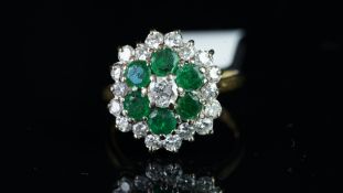 An emerald and diamond cluster ring, three tiered cluster, set with a central round brilliant cut