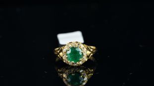 An emerald and diamond set cluster ring, central circular mixed cut emerald measuring an estimated