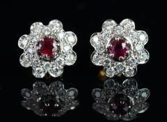 A pair of ruby and diamond floral stud earrings, single round cut ruby, surrounded by brilliant