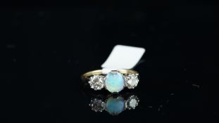 Three stone opal and diamond ring, central 6.5xmm round opal cabochon, mounted with a brilliant