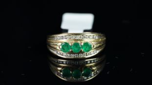 An emerald and diamond band ring, set with three central round cut emeralds, and diamond detail, set