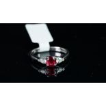 A spinel and diamond ring, central oval cut red spinel weighing an estimated 0.63ct, with a pear cut