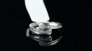 Diamond crossover ring, mounted in unmarked white metal, stamped DIA inside shank, finger size L,