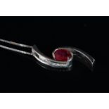 A ruby and diamond pendant, oval cut ruby in a crossover setting, set with round brilliant cut