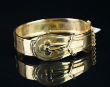 Antique hinged buckle bangle, mounted in unmarked yellow metal, with safety chain, set with a dark