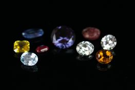 Selection of nine loose stones including an oval ruby, a round synthetic white sapphire, an oval
