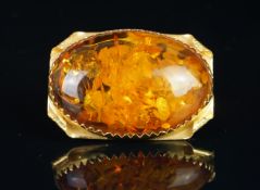 An amber brooch, large cabochon cut amber measuring an estimated 40 x 30mm, in a yellow metal frame,