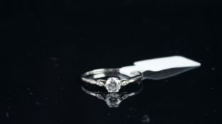 Single stone round brilliant cut diamond ring, with one small diamond set to each shoulder,