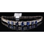Sapphire and diamond bangle, seven graduated oval cut sapphires, measuring from 6 x 4.8 to 4.5 x 3.