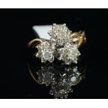 A diamond cluster ring, designed as three daisy clusters, each set with a central round brilliant