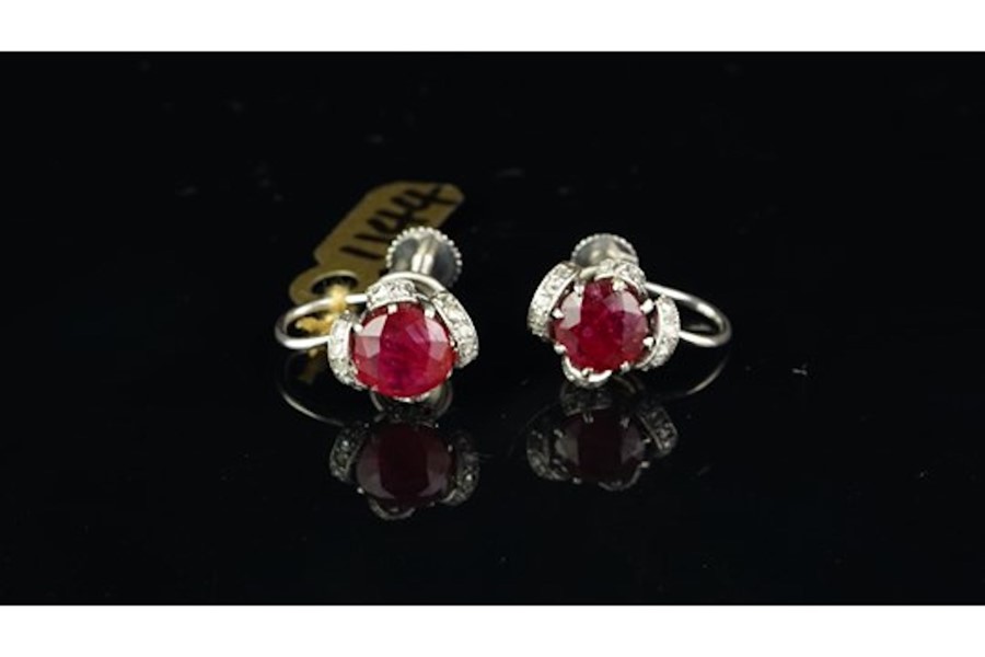 Ruby and diamond screw back ear clips, set in unmarked white metal, central round ruby with