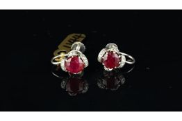 Ruby and diamond screw back ear clips, set in unmarked white metal, central round ruby with