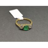 Three stone emerald and diamond ring, central square step cut emerald measuring approximately 5.52 x