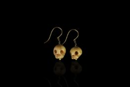 Carved bone skull earrings, suspended from yellow gold french wires