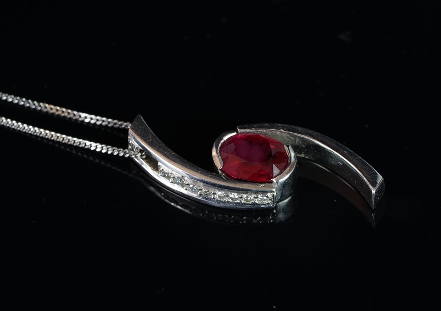 A ruby and diamond pendant, oval cut ruby in a crossover setting, set with round brilliant cut