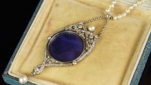 A pearl and diamond locket pendant set in unmarked white metal, central circular locket, within an