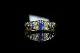 Sapphire and diamond carved half hoop ring, oval cut sapphire centre with four old cut diamonds