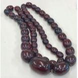 Long string of graduated cherry amber / bakelite beads good internal streaking largest bead measures