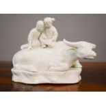 A white porcelain water buffalo with children seated upon its back, 17cm high.