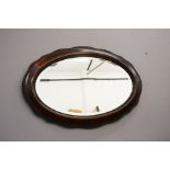 A rosewood and ebonised ripple moulded and shaped wall mirror.