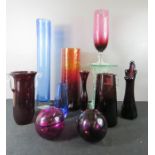 A group of Blenko glassware, including two tall vases, one in blue and the other in red-orange, a
