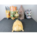 A group of painted treen carved masks and a brass ewer.