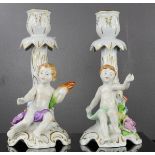 A pair of German porcelain candlesticks, modelled with cherubs, 20cm high.